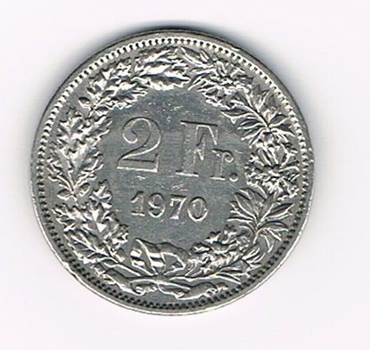 Pièce de 2 Francs argent Suisse émise en 1970 tranche striée. Descriptif. Helvetia, le personnage allégorique féminin suisse, vêtue d'une toge, tient une lance.